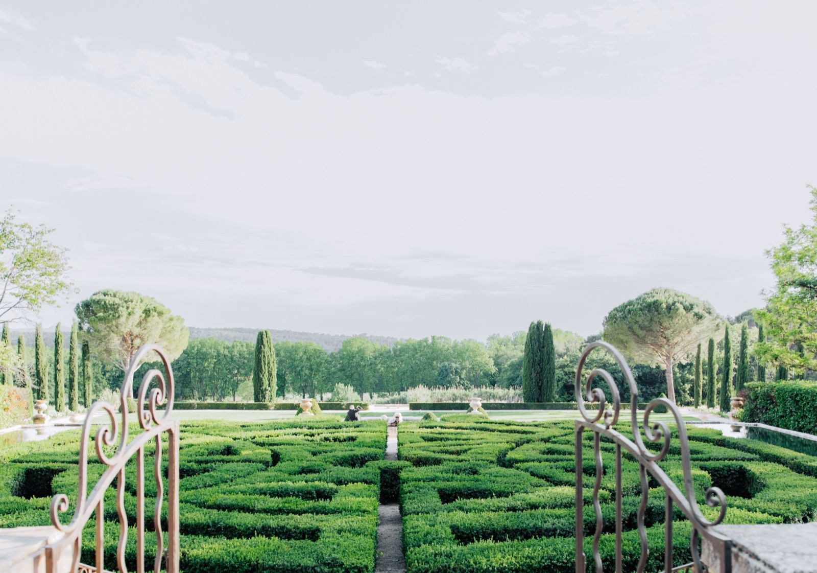 Jardin à la française vu depuis un portail en fer forgé